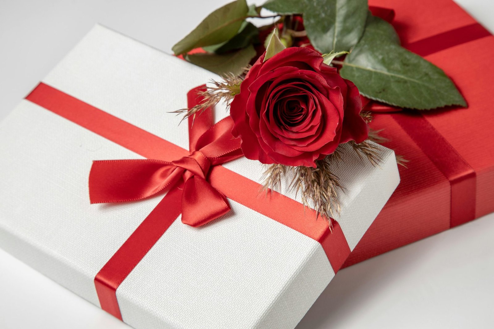 Close-up of beautifully wrapped gift boxes with a red rose, perfect for romantic occasions.